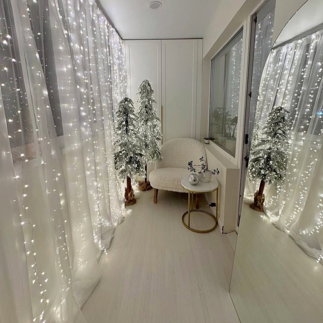 Decorative string lights on sheer curtains in a room with a white sofa and small table.